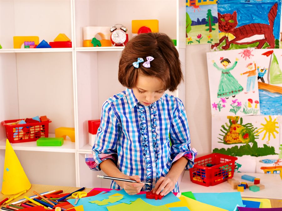 Niña haciendo manualidades con cartulinas de colores