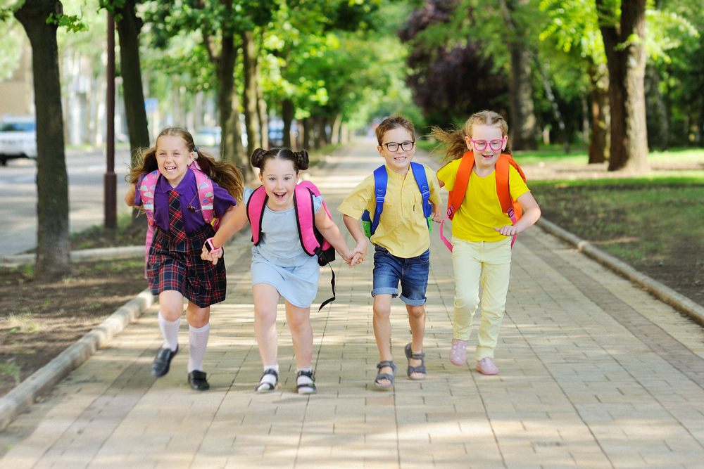 Niños caminando juntos por un paseo arbolado